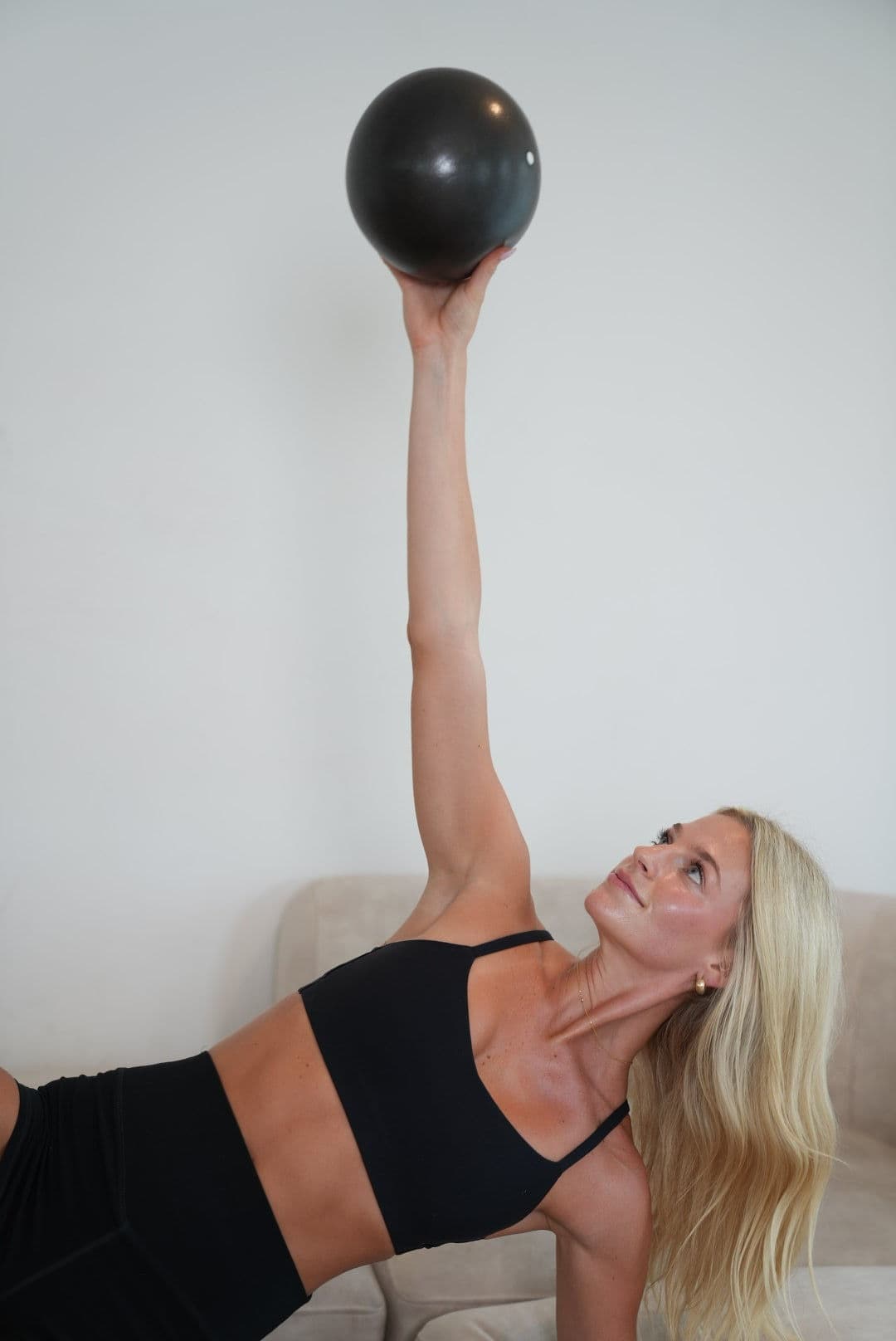 Brittany mid-exercise, reaching a ball overhead